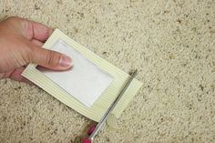 someone is cutting paper with a pair of scissors on the floor next to carpeting