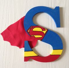 the letter s is made out of paper and has superman's cape on it