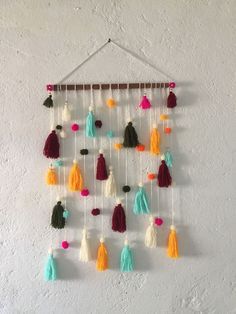 a multicolored wall hanging with tassels and pom - poms