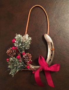 a christmas decoration made out of horseshoes and pine cones with a red ribbon tied around it