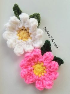 two crocheted flowers sitting next to each other