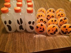 plastic bottles filled with orange and black jack - o'- lantern pumpkins on top of a wooden table