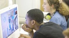 two people sitting in front of a computer screen