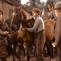 three men standing next to each other with horses in front of them and one man holding the horse's bridle