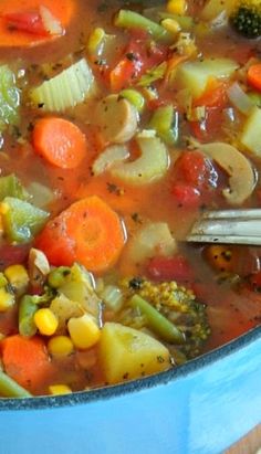 a blue pot filled with soup and vegetables