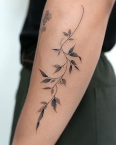 a woman's arm with a tattoo on it that has leaves growing out of it