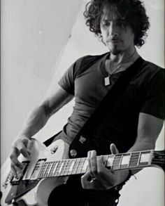 a man with curly hair playing an electric guitar