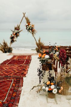 an outdoor ceremony set up on the beach with flowers and pamodia in wicker baskets