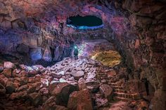 a man standing in the middle of a cave filled with lots of rocks and boulders