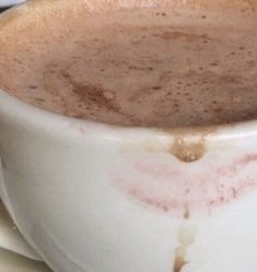 a white cup filled with hot chocolate on top of a table