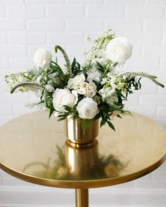 white flowers in a gold vase on a table