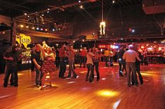 a group of people are dancing on the dance floor in a large room with wooden floors