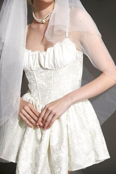 a woman in a white wedding dress with a veil over her head and hands on her hips