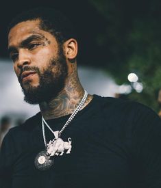 a close up of a person wearing a black shirt with tattoos on his neck and chest