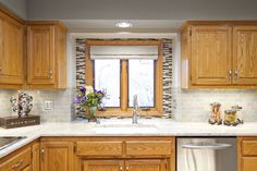 a kitchen with wooden cabinets and white marble counter tops, an open window above the sink