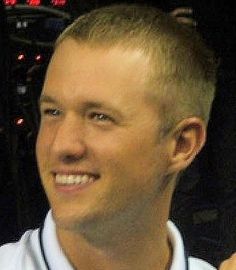 a man in a baseball uniform is smiling and holding a cell phone up to his ear