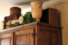 there is a cabinet that has many items on top of it, including a vase and clock