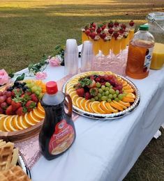 a table topped with plates of fruit and waffles next to bottles of juice