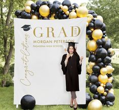 a woman standing in front of a graduation sign with balloons around her and the graduate's name on it