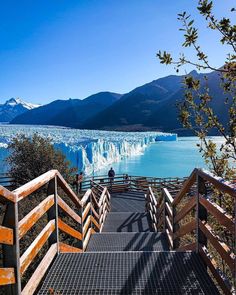 stairs lead down to the water and icebergs in the distance with mountains in the background