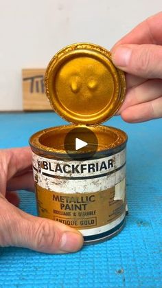 someone is opening up a tin with gold paint