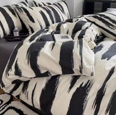 a bed with black and white comforters on top of it next to a night stand