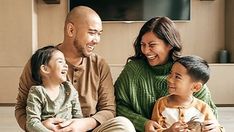 a family sitting on the floor laughing and looking at something in front of their face