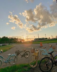 several bicycles are parked in a parking lot with the sun shining through clouds above them