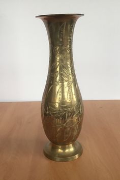 a gold vase sitting on top of a wooden table