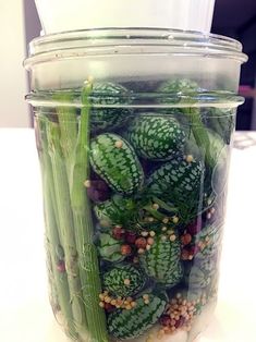 a jar filled with green vegetables sitting on top of a table