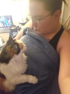 a woman laying in bed with a cat on her lap