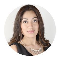 a woman with long hair wearing a black dress and pearls on her necklace is looking into the camera