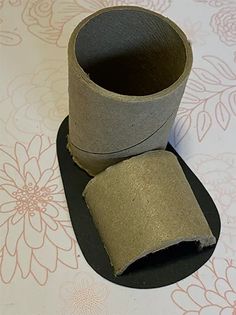 a roll of toilet paper sitting on top of a black mat next to a cup