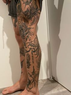 a man with tattoos on his legs standing in front of a door