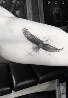 a black and white photo of a bird tattoo on the right arm, with an eagle flying above it