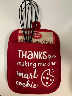 a red oven mitt hanging on the wall with some chocolate chip cookies in it