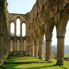 the interior of an old building with many arches and grass in front of it on a sunny day