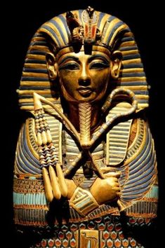 an egyptian statue is shown in gold and blue colors, with two swords on his chest