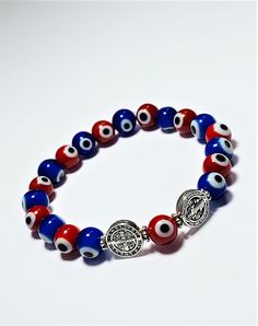 A protection bracelet fit for anyone! This bracelet comes blessed and ready to be use by the wearer. It has been elaborated with red and blue evil eye beads followed by 2 stainless steel St. Benedict charms, all strung together with high quality elastic making it super easy to put on! The Saint Benedict Medal is considered one of the most powerful symbols of protection. It is used for prayer against evil, for strength in a time of temptation, for peace among ourselves and the nations of the worl Symbolic Multicolor Round Beads Bracelets, Symbolic Multicolor Round Beads Bracelet, Spiritual Red Stretch Bracelet Gift, Spiritual Red Stretch Bracelet As Gift, Handmade Red Symbolic Beaded Bracelets, Red Symbolic Handmade Bracelets, Symbolic Multicolor Bracelets As Gift, Adjustable Red Stretch Bracelet Spiritual Style, Red Spiritual Charm Bracelet