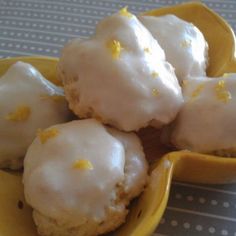 a yellow bowl filled with frosted donuts on top of a table