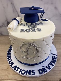 a white cake with blue decorations and a graduation cap on top that reads congratulationss denver