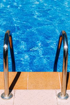 two metal hand rails next to a swimming pool