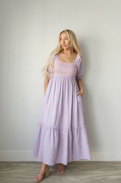 Discover a perfect blend of style and comfort with our Embroidered Gauze Midi Dress in Lavender. The lightweight gauze fabric is adorned with delicate floral embroidery and a bold orange contrast, making it perfect for any occasion. The smocked waist adds a flattering fit and the midi length offers versatility for all body types. Embrace the lavender and orange blend and make a statement with this beautiful dress. gauzy cotton smocked bodice elbow length sleeves side pockets embroidered lined mi Lavender Floral Embroidered Dress For Spring, Embroidered Lavender Dress For Spring, Purple Embroidered Dress For Summer, Spring Lavender Embroidered Dress, Spring Embroidered Lavender Dress, Lavender Embroidered Spring Dress, Spring Purple Embroidered Dress, Spring Purple Embroidered Dress With Floral Detail, Curvy Date Night Outfit