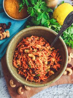 a bowl filled with carrots and nuts next to other foods on a cutting board