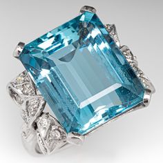 This striking vintage cocktail ring is centered with an emerald cut aquamarine, weighing 10.94 carats, in a four-prong setting. The shoulders are each accented with a bow design with milgrain details and is bead set with nine (9) round single cut diamonds. The ring measures 16.8mm at the top, rises 8.9mm above the finger, tapering to 1.9mm wide and 0.9mm thick at the base of the shank. This ring is currently a size 5. There is a tiny nick on the face of the stone. Aquamarine Stone Ring, Stunning Aesthetic, Aquamarine Color, Aquamarine Birthstone, Vintage Cocktail Ring, Diamond Cocktail Ring, Diamond Jewelry Designs, Aquamarine Jewelry, Diamond Cocktail Rings