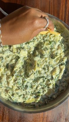 a woman's hand holding onto a bowl of food