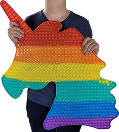 a person holding up a large piece of art made out of legos that looks like a rainbow fish