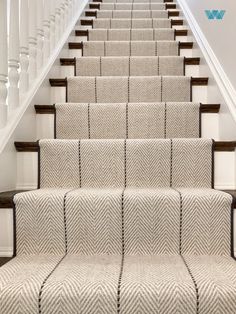 a set of stairs with carpeted treads and wooden handrails, leading up to the second floor