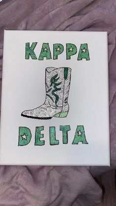 a white sign that says kapa delta with green and white boots on the bottom