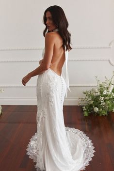 a woman in a white dress standing on a wooden floor with her back to the camera